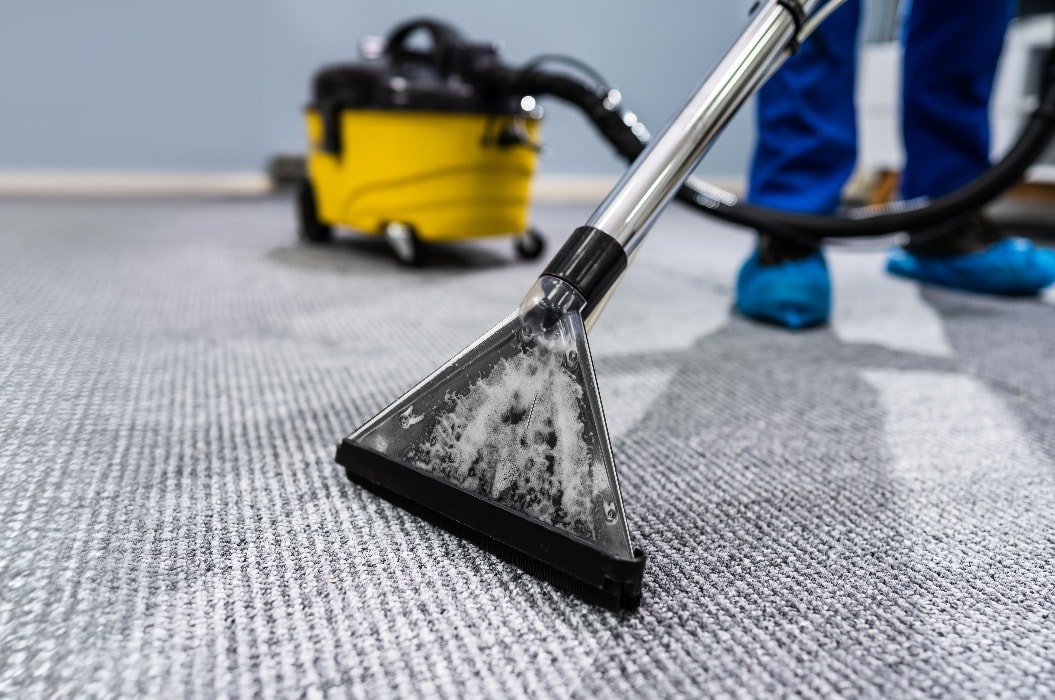 Person reinigt Teppichboden mit Staubsauger