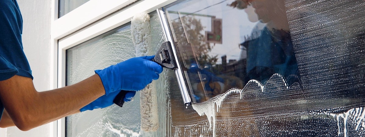 Mann reinigt die Fenster bei einer Gebäudereinigung